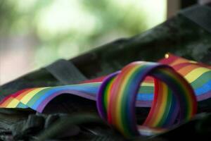 arco Iris bandeira e arco Iris pulseiras em camuflar fundo, conceito para celebrações do lgbt pessoas dentro orgulho mês por aí a mundo, suave e seletivo foco em pulseira. foto