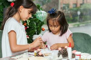 dois pequeno irmãs tendo Diversão enquanto fazer Natal natividade trabalhos manuais com às casa - real família foto