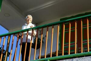 Senior mulher às uma tradicional colorida sacada dentro a lindo colonial Cidade do Salento dentro a região do quindio dentro Colômbia foto