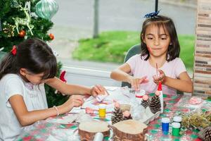 dois pequeno irmãs tendo Diversão enquanto fazer Natal natividade trabalhos manuais com às casa - real família foto