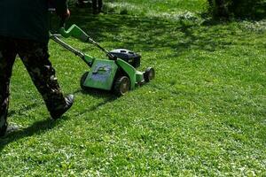 comum Serviços jardineiro trabalhador homem usando gramado cortador de grama para Relva corte dentro cidade parque. foto