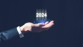 2024 o negócio planejamento e estratégia conceito, homem de negocios segurando virtual ícone do a ano 2024, marketing financeiro e pesquisa análise, investimento tendências Próximo Novo ano foto