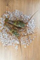 dois ise lagostas a partir de Japão colocada em uma de madeira borda fundo com gelo foto