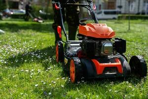 comum Serviços jardineiro trabalhador homem usando gramado cortador de grama para Relva corte dentro cidade parque. foto