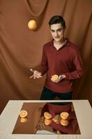 uma bonito homem lança a laranja perto a mesa com uma espelho foto