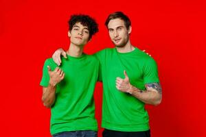 dois homens abraçando dentro verde Camisetas em uma vermelho fundo foto