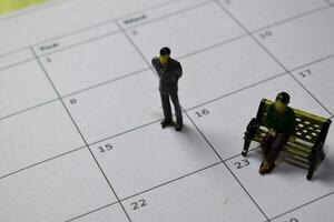 miniatura pessoas em pé e sentado elas pensando salário às 15º em calendário. agendar, lembrete conceito foto