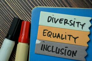 diversidade igualdade inclusão escrever em uma pegajoso Nota isolado em escritório escrivaninha. foto