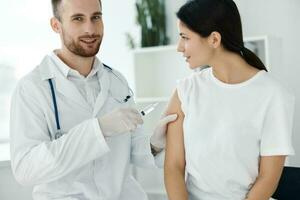 profissional médico injeta uma vacina em uma fêmea pacientes ombro foto