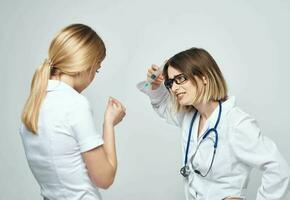 uma mulher detém uma seringa dentro dela mão e uma fêmea paciente dentro uma branco camiseta é assustado modelo foto