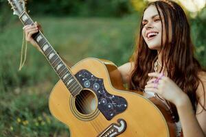 lindo mulher jogando guitarra dentro natureza dentro uma hippie verão olhar, cantando canções estilo do vida sem preocupações foto