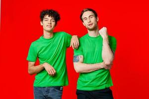dois alegre amigos dentro verde Camisetas estão em pé Próximo para cada de outros foto