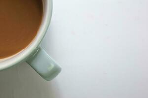 fechar acima quente cappuccino café dentro uma azul copo isolado em uma branco fundo foto