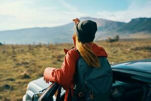 mulher perto carros gesticulando com dela mãos em natureza dentro a montanhas outono mochila viagem turismo foto