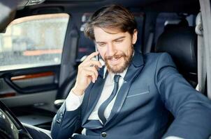 empresários dentro uma terno dentro uma carro uma viagem para trabalhos comunicação de telefone foto