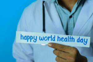 médico segurando uma cartão com texto feliz mundo saúde dia. médico e cuidados de saúde conceito. foto