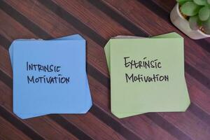 intrínseco motivação e extrínseco motivação escrever em pegajoso notas isolado em de madeira mesa. foto