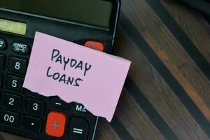 conceito do dia do pagamento empréstimos escrever em pegajoso notas com calculadora isolado em de madeira mesa. foto