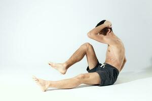 exercícios jovem atleta dentro cinzento calção e a inflado tronco ginástica exercite-se foto