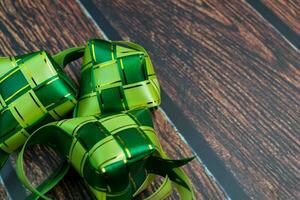 ketupat ou arroz bolinho de massa em uma de madeira mesa. Ramadã kareem e eid Mubarak conceito foto