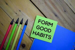 Formato Boa hábitos escrever em uma pegajoso Nota isolado em de madeira fundo. foto