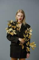 glamouroso mulher moda dourado folhas dentro Preto Jaqueta estúdio modelo inalterado foto