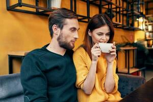 bonito homem dentro suéter e mulher com uma copo do café encontro amor restaurante cafeteria foto