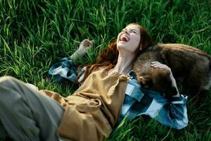 uma mulher mentiras em a Relva sorridente e abraço dela cachorro dentro natureza dentro uma parque dentro a verão pôr do sol. a conceito do saúde e amor para animais, tratamento contra carrapatos foto