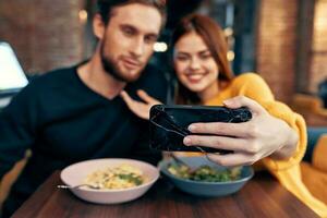 jovem casal dentro uma restaurante faz uma selfie em a telefone comunicação foto