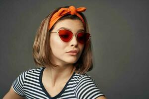 mulher vestindo oculos de sol dentro uma listrado camiseta com uma curativo em dele cabeça posando moda foto