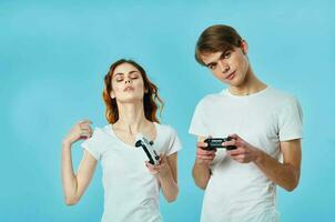 jovem casal dentro branco Camisetas com joysticks dentro mãos jogando entretenimento foto