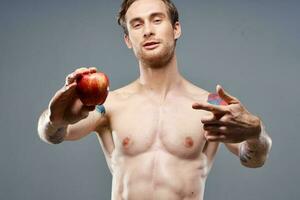 Atlético homem com uma bombeado tronco e uma tatuagem em dele braço vermelho maçã saúde foto