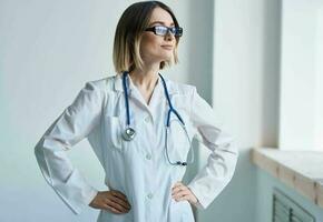 mulher com profissional estetoscópio médico dentro médico vestido dentro brilhante quarto foto