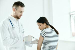 masculino médico dando a injeção para uma paciente dentro uma hospital coronavírus foto