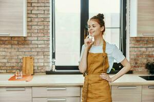 bonita mulher dentro a avental dentro a cozinha tarefas domésticas família conceito foto