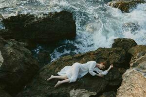 descalço mulher deitado em rochoso costa com rachaduras em rochoso superfície inalterado foto