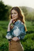 retrato do uma jovem menina em uma verão dia dentro a raios do a configuração Sol com uma lindo sorriso, vestido Como uma agricultor e jardineiro foto