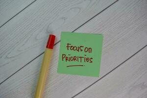 foco em prioridades escrever em pegajoso notas isolado em de madeira mesa. foto