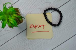 zakat escrever em pegajoso notas isolado em de madeira mesa. foto