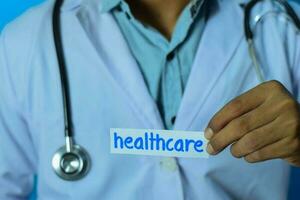 médico segurando uma cartão com texto assistência médica. médico e cuidados de saúde conceito. foto
