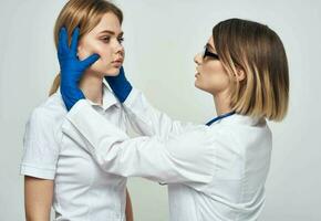 uma mulher médico dentro uma médico vestido e azul luvas examina a pacientes face foto
