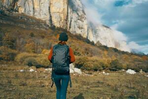 mulher dentro outono em repouso dentro natureza dentro a montanhas Sol azul céu panorama mochila foto