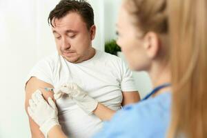 uma mulher médico injeta uma vacina para dentro uma do homem mão fechar-se foto