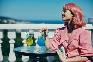 retrato do lindo mulher bebendo uma coquetel em a terraço feliz fêmea relaxante foto