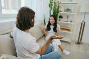 uma homem e uma mulher sentar em a sofá às casa dentro branco Camisetas e gritando comunicar escandalosamente Faz não Compreendo cada outro. uma brigar dentro a família do dois esposas e agressão, triste emoções foto