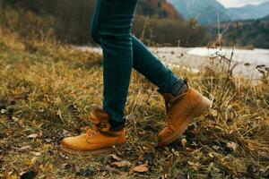 fêmea pernas dentro chuteiras e jeans em natureza dentro outono dentro a montanhas foto