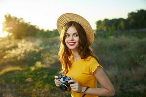 bonita mulher com Câmera em natureza fresco ar chapéu vermelho lábios passatempo foto
