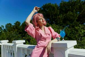 retrato do lindo mulher com Rosa cabelo verão coquetel refrescante beber relaxamento conceito foto