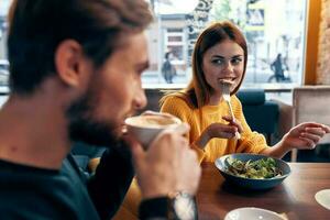 emocional homens e mulheres às uma mesa dentro uma cafeteria Diversão casado casal refeição salada foto