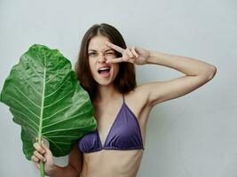 alegre mulher segurando mãos perto face verde folha roupa de banho emoções fechar-se foto